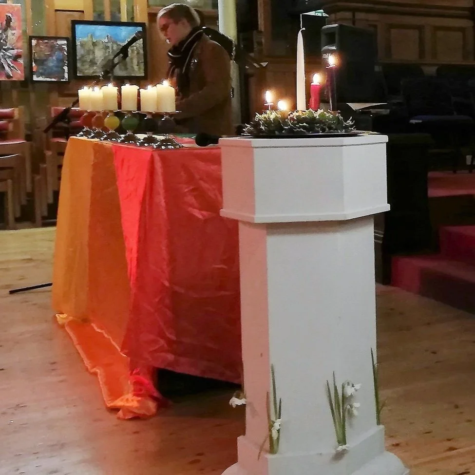  Beth Powell sharing her reflection at the Open Table carol service in St Bride’s Liverpool on Sunday 19th December 2021.  The service was streamed on Facebook Live, but due to technical issues, the sound quality was variable. We have published an edited version of the video on  our YouTube channel , with subtitles to make it more accessible. You can watch it below [44 mins]. As usual,  Liverpool Rainbow Chorus , the city’s LGBT+ choir, were booked to perform much of the music, but due to positive Covid tests on the day, most of the choir could not attend. So we shared videos they and others made for last year’s online service instead. We hope you like it.   You can download the order of service here . Please note that some of it is different because of the absence of the choir and the need to edit parts where the sound was not recorded. 