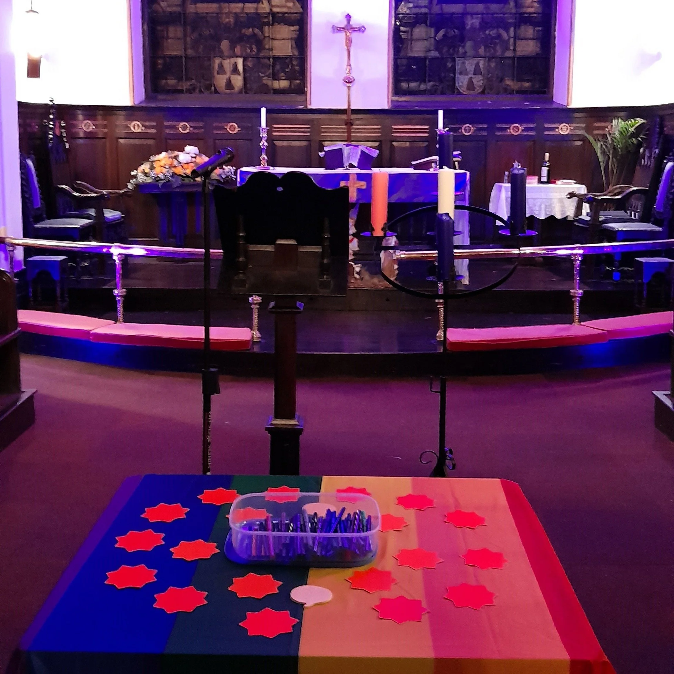  On the sanctuary at Sacred Trinity Church, Salford, in front of the altar, lectern and advent wreath, is a table draped in a raibow flag, with bright card stars and speech bubbles and a box of felt-tip pens for people to share feedback about the exhibition during the servce. Click on the image to enlarge it. 