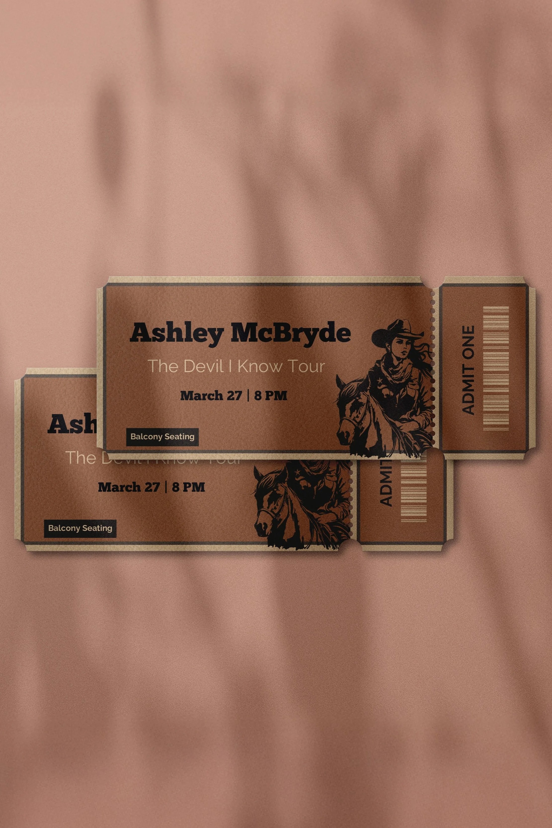 Two concert tickets for Ashley McBryde's 'The Devil I Know Tour' on March 27 at 8 PM, seated on a pink fabric background. The tickets feature an illustration of a woman wearing a cowboy hat and riding a horse, with barcode and seating information.
