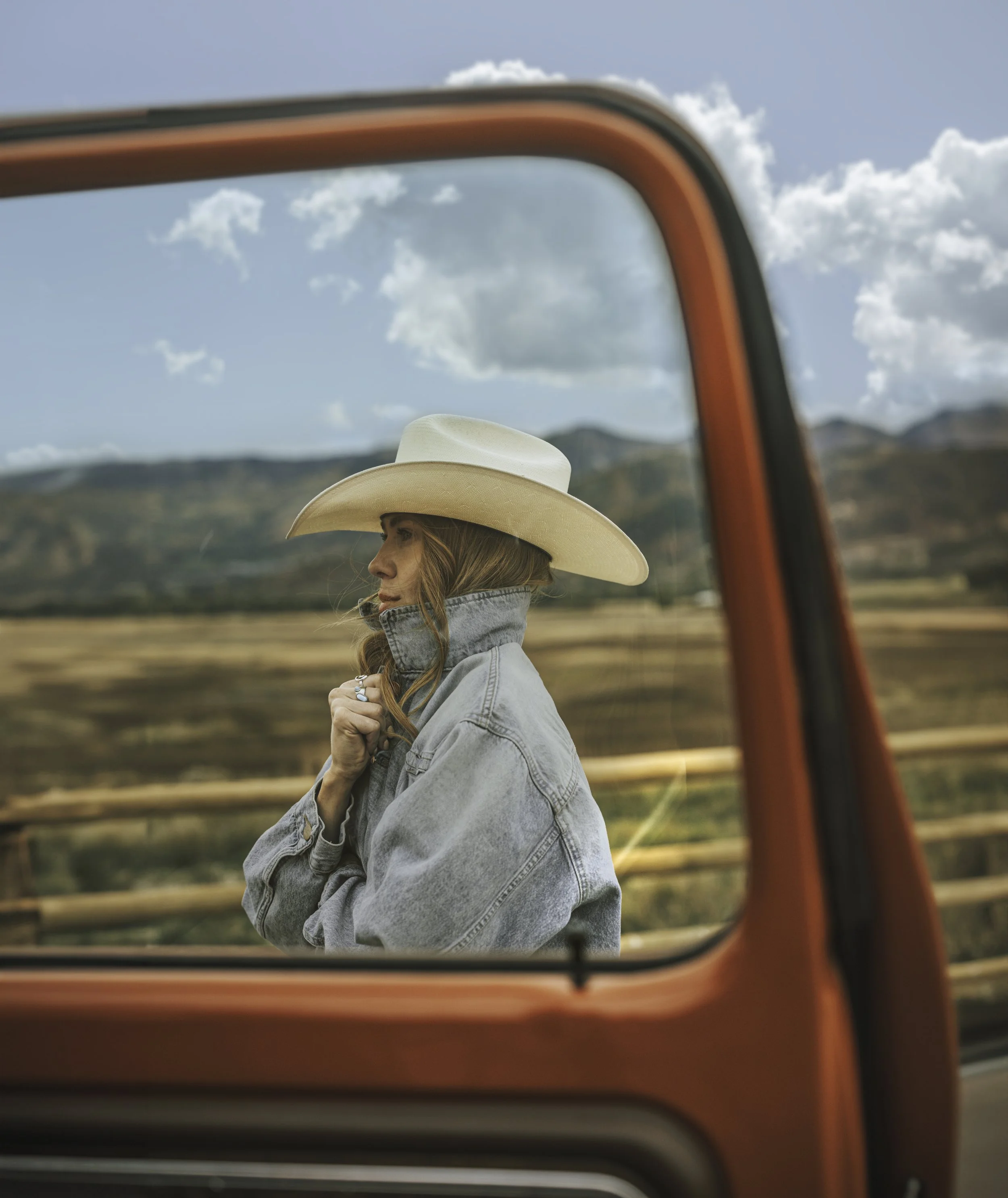 Wrangler Original fragrance lifestyle campaign featuring woman in cowboy hat framed by vintage truck window in rural Western landscape