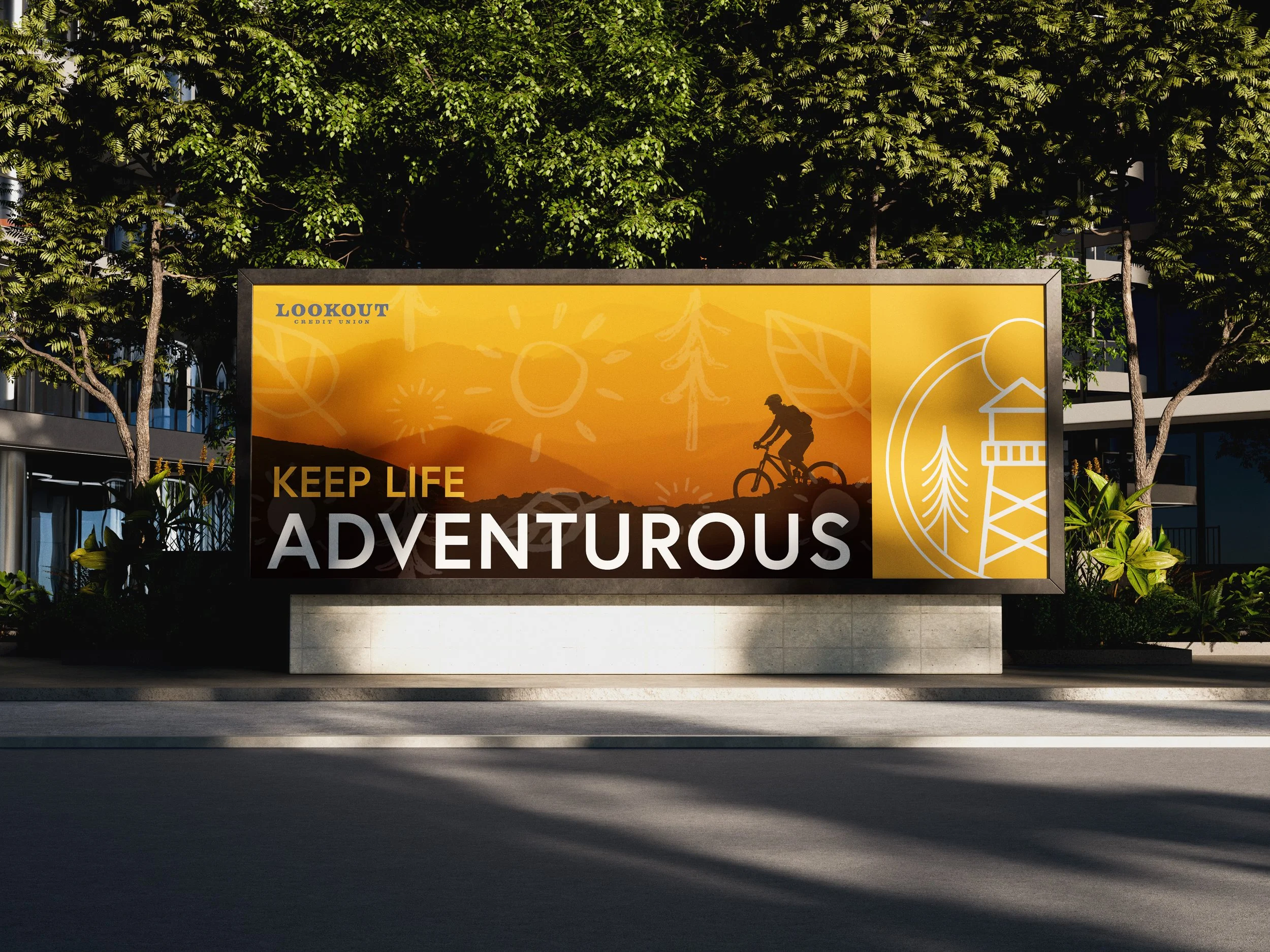 Billboard with a sunset scene showing a person riding a bicycle on a mountain trail, with the text 'Keep Life Adventurous' and a graphic of a forest and mountain landscape.