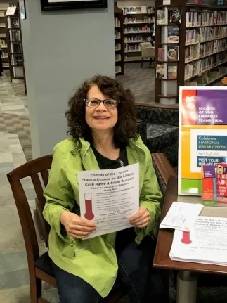 Jill sells Take A Chance on the Library Raffle tickets in the Library.