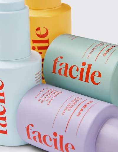 Assorted colorful "facile" skincare bottles, including clear targeted acne serum, anti-aging serum.