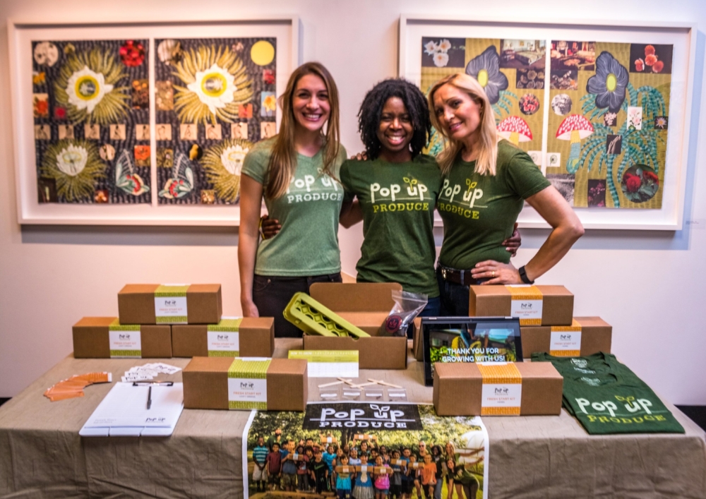 Vendor booth setup for Repurposed: Fashion Show + Auction. Shown (left to right): Pop Up Produce Founder, Amanda Zullo; Kit Owner and Volunteer, Demetria Cox; Kit Owner and Volunteer, Nina Zullo
