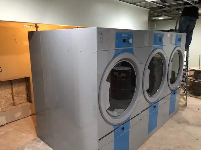 This dryer bay was inexplicably just four feet deep. With three feet of clearance behind the dryers that leaves the dryers only sticking into the bay one foot. You can see the fur-down hitting close to the back seam of the dryer. It is not a fatal problem; the dryers can be sealed into the bay and air flow will work. The final look just highlights the lack of design or coordination.