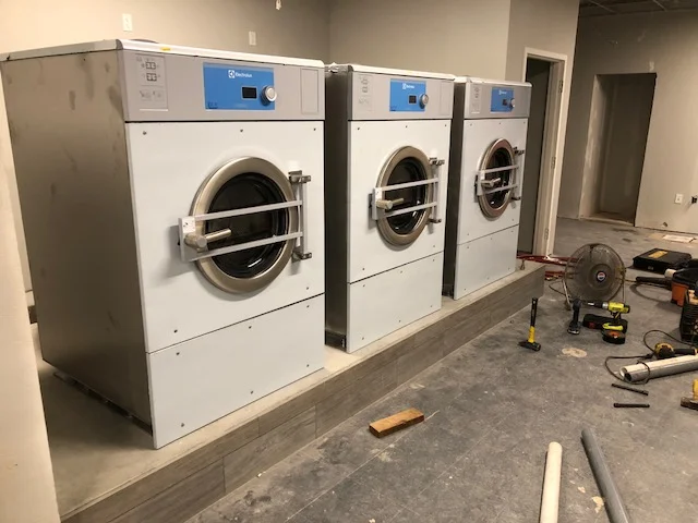 Some W5280Xs being installed. Note the fancy tile on the front of the pad. Not a bit of it was chipped on install. Last, these are stainless machines. The front, protective stickers have yet to be peeled. We'll wait until construction is over.