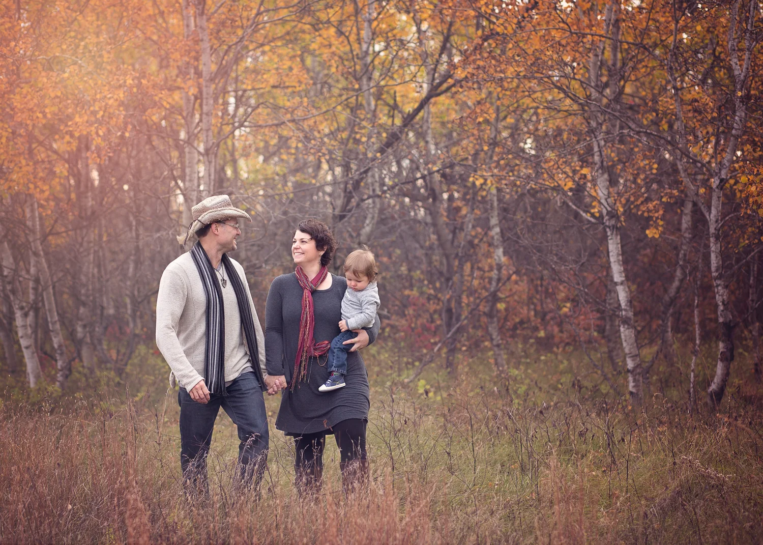 Young family of three walking in the fall trees in Birds Hill Park near Winnipeg.