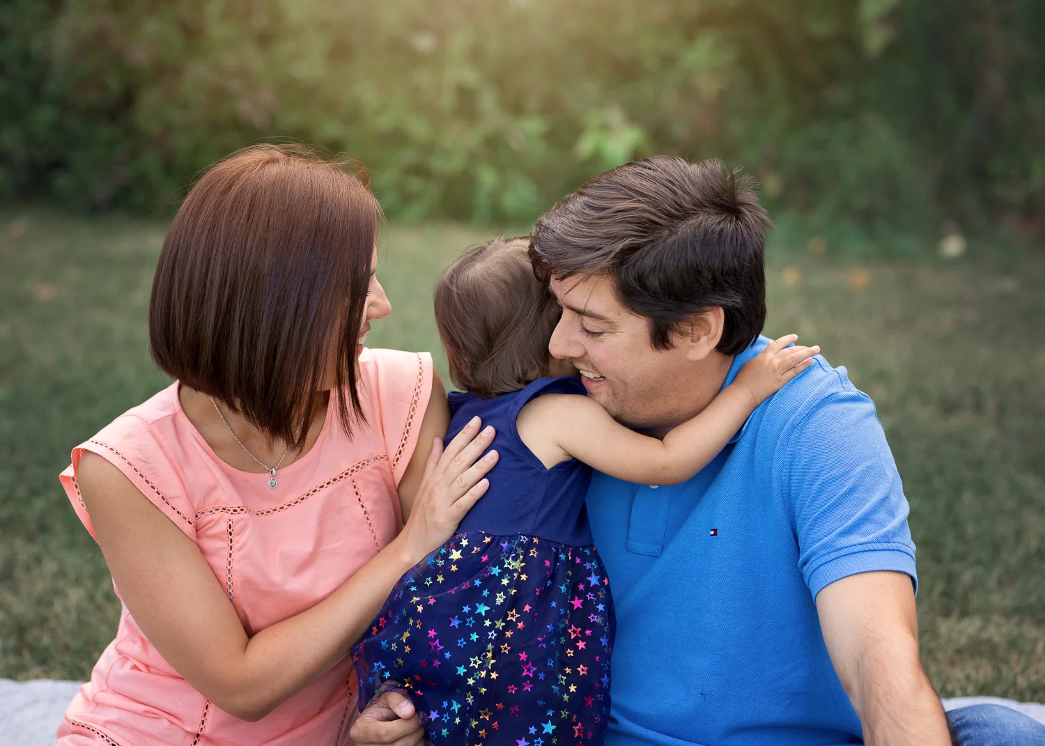 Little girl giving daddy a hug during summer family photos in Kings Park in Winnipeg.