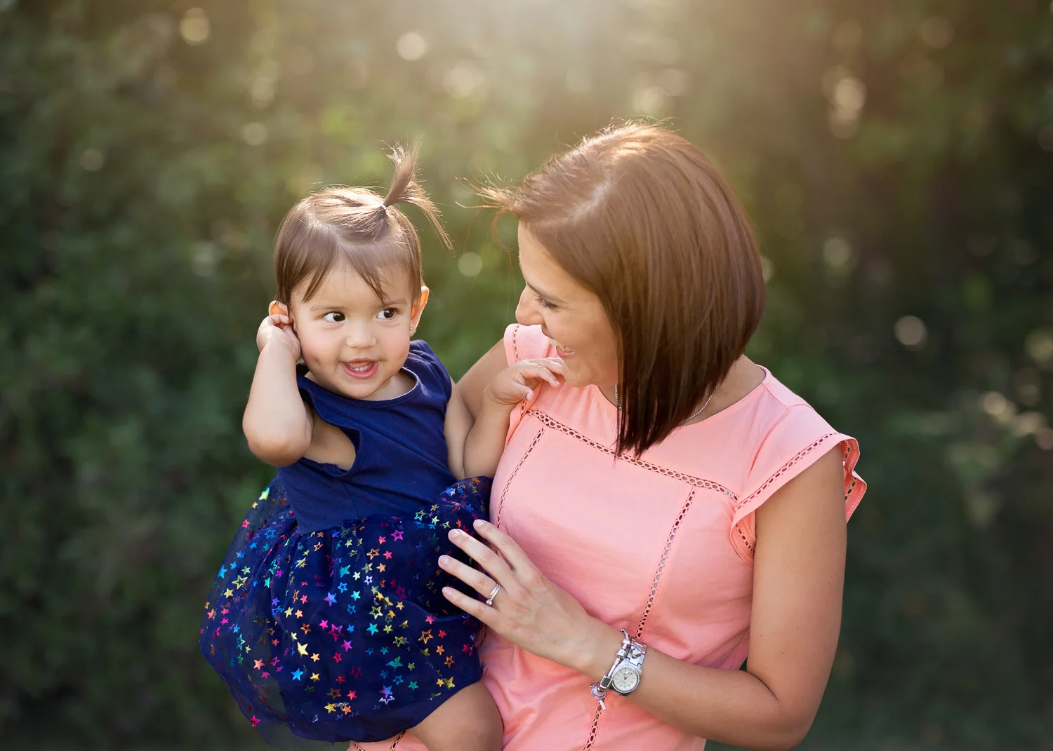 Little girl giggling in her mothers arm during summer family photo shoot in Winnipeg.
