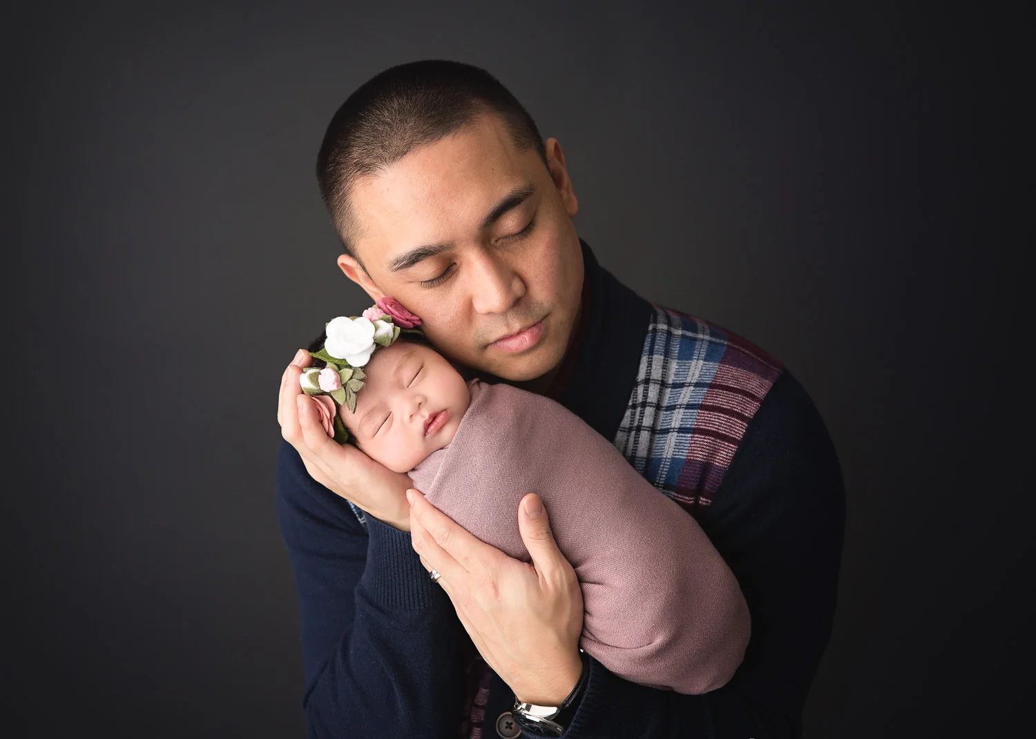 Father holding his new baby girl durin newborn posed photo shoot in Winnipeg Studio.
