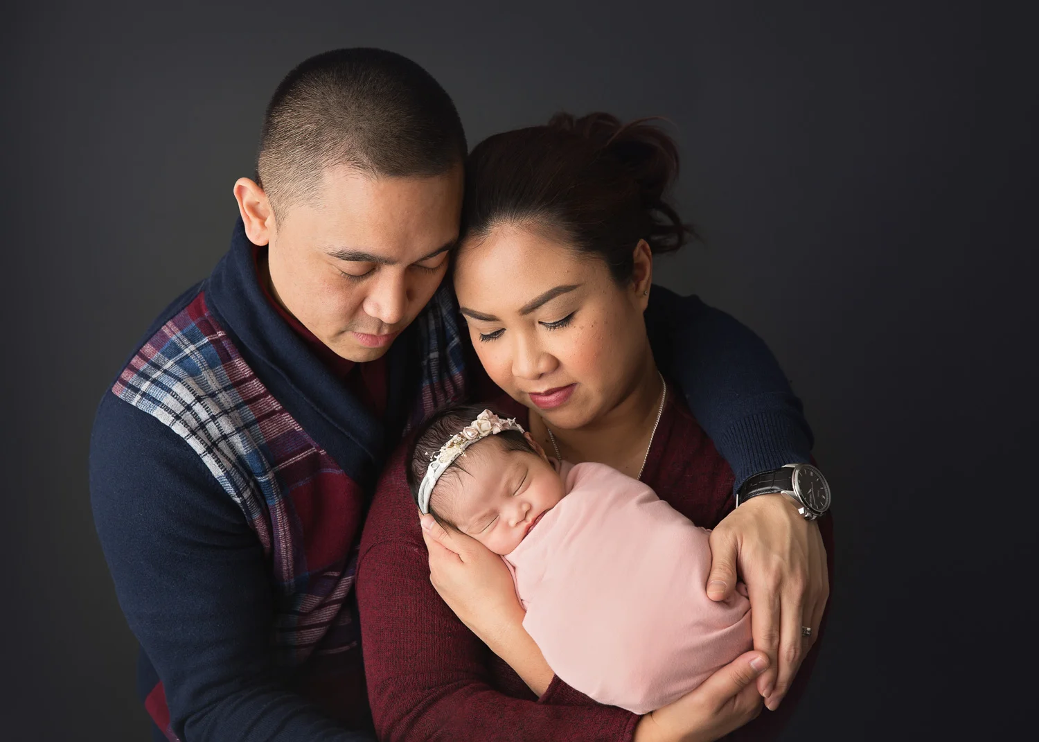 Parents lovingly gazing down at their new baby girl during newborn photosession in Winnipeg Studio.