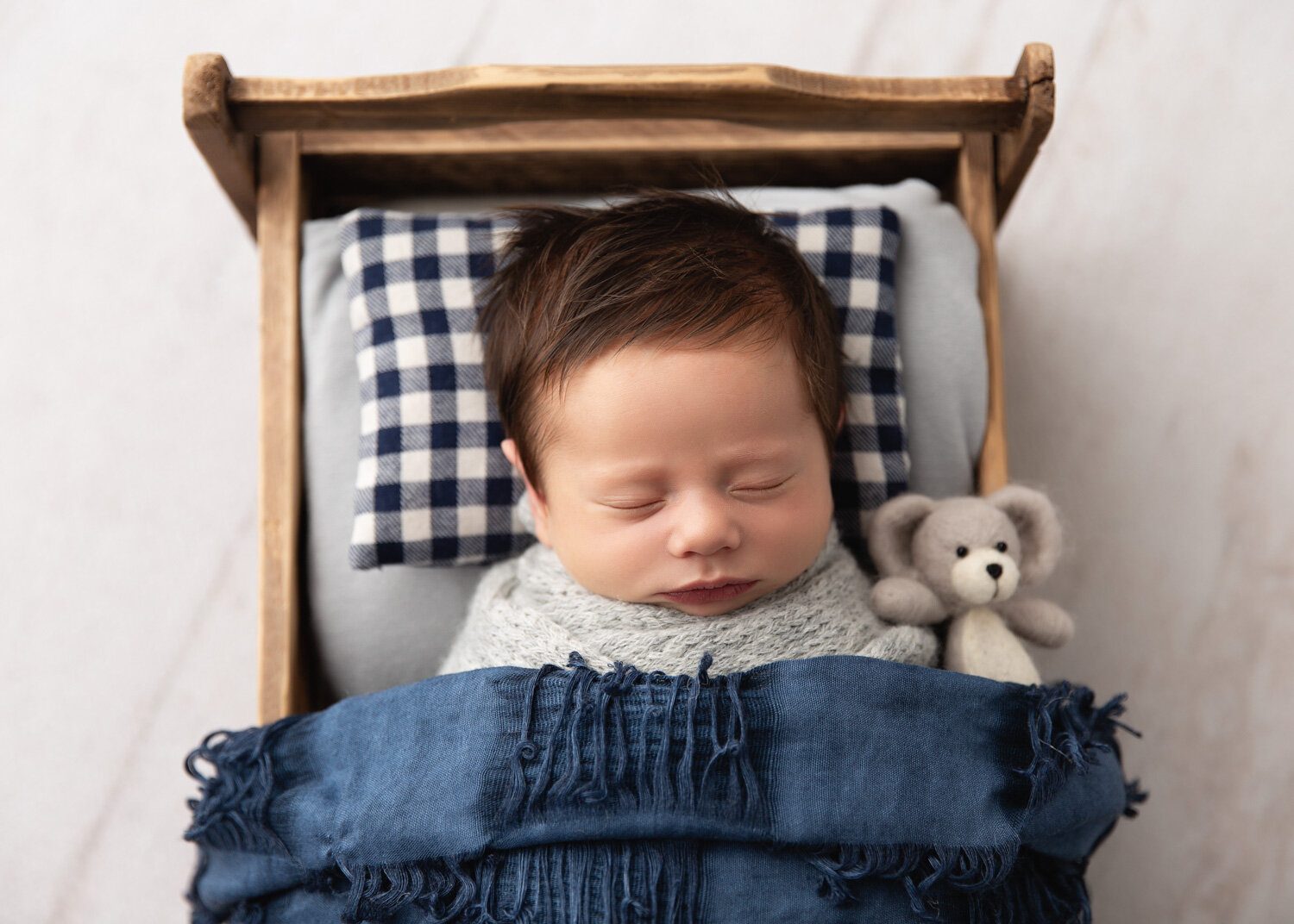  Baby boy with lucious dark hair in bed prop during newborn photography shoot in Winnipeg with Sue Skrabek 