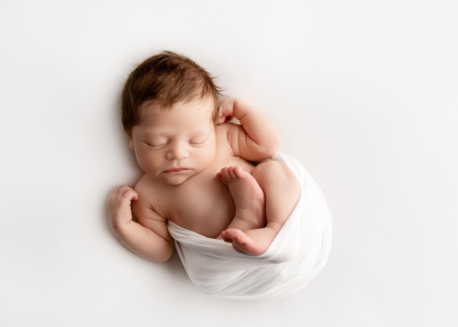  Classic baby boy wrapped in white relaxed posed with Sue Skrabek Photography during newborn session in Winnipeg 