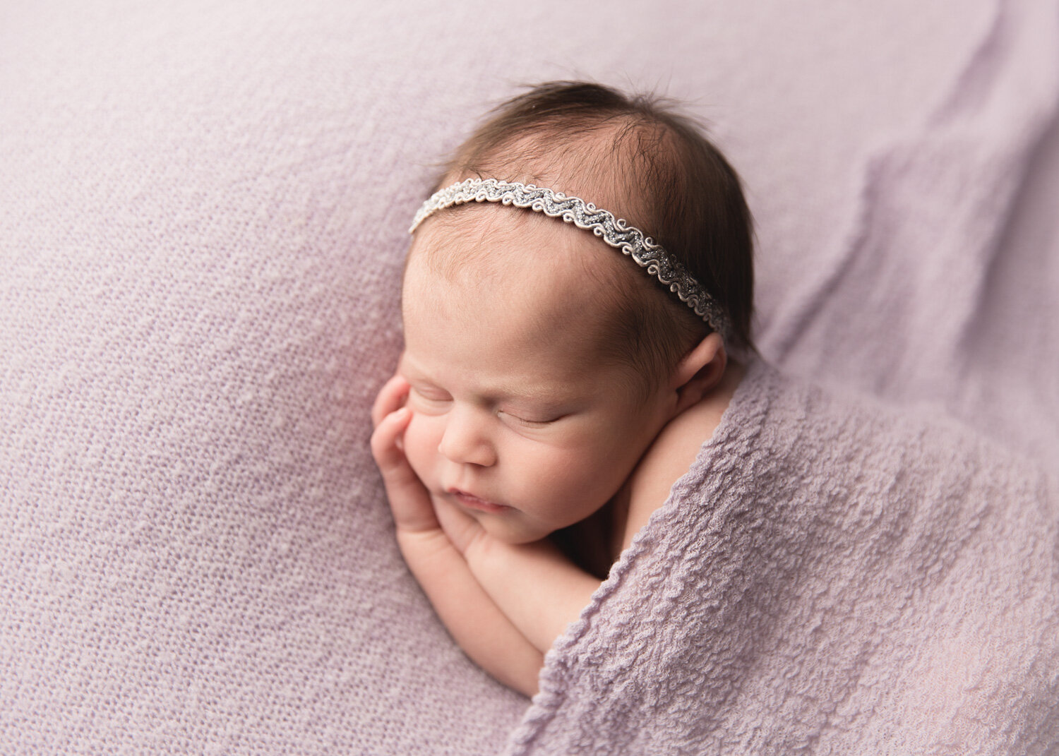  Newborn baby girl with lavender wrap posing during photosession in Winnipeg with Sue Skrabek 