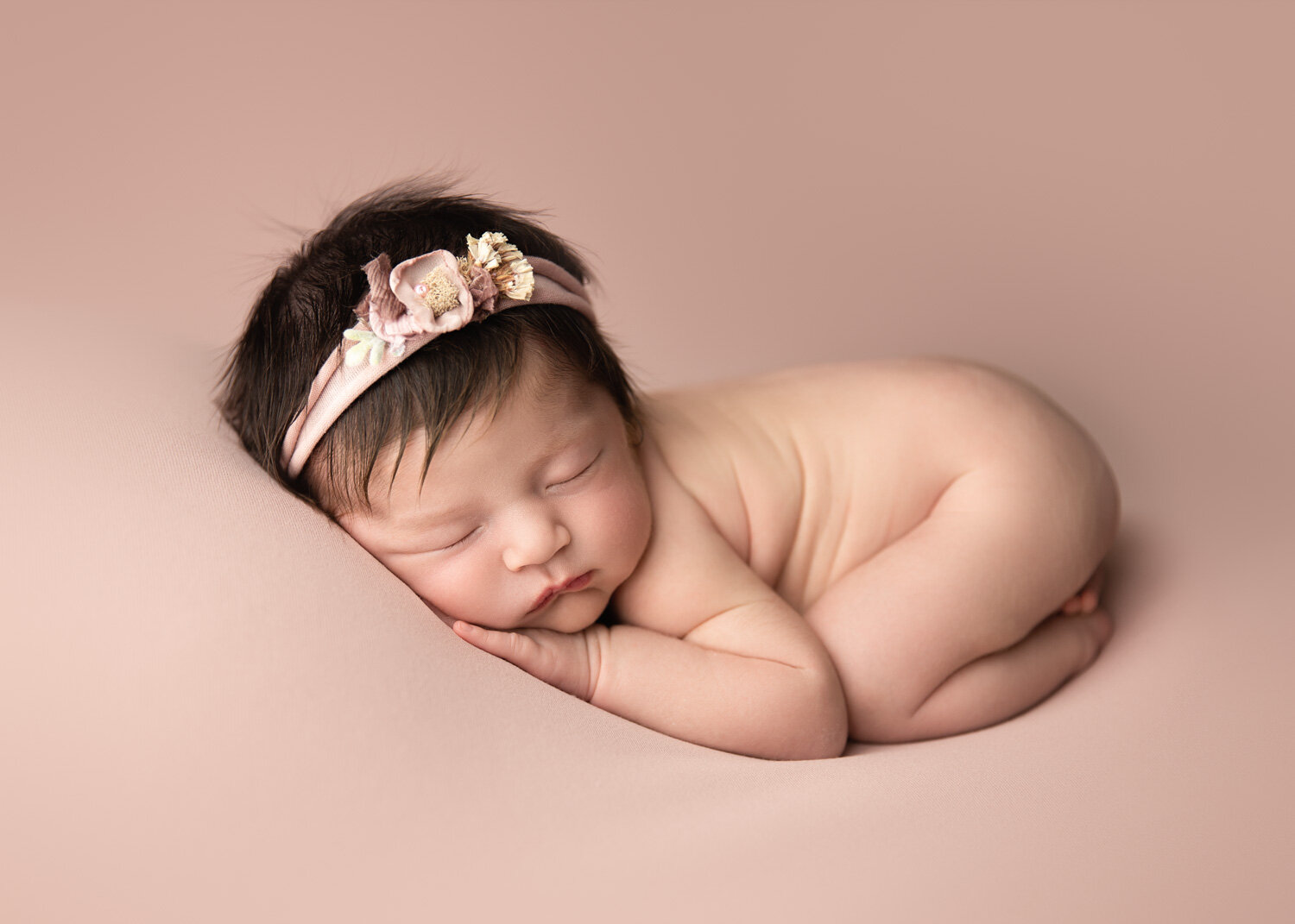  Baby girl lying on blush pink backdrop with soft pink blanket in Winnipeg 
