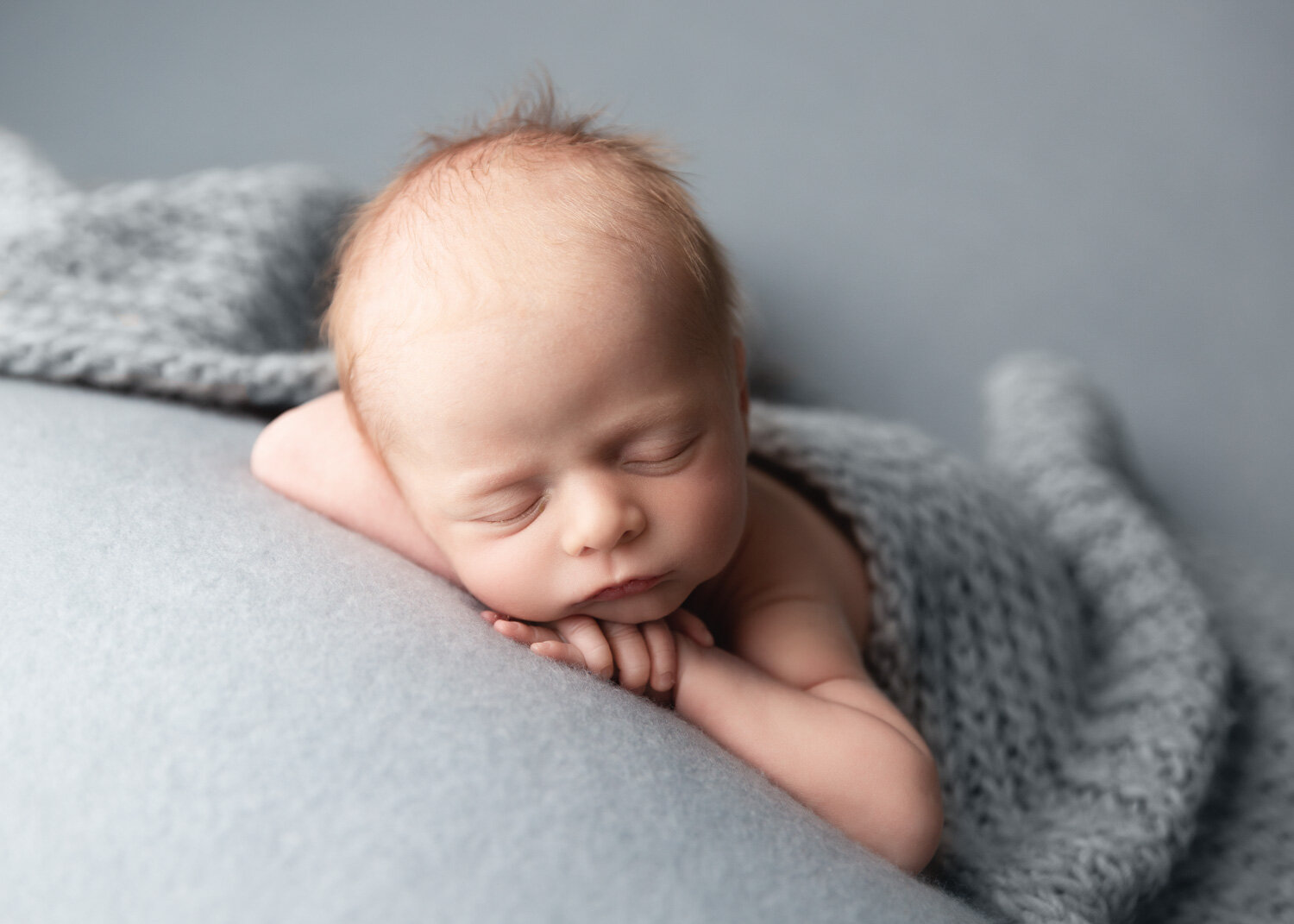  Adorable baby boy lying on blue blanket with chin on hands in Winnipeg newborn studio with Sue Skrabek Photography 