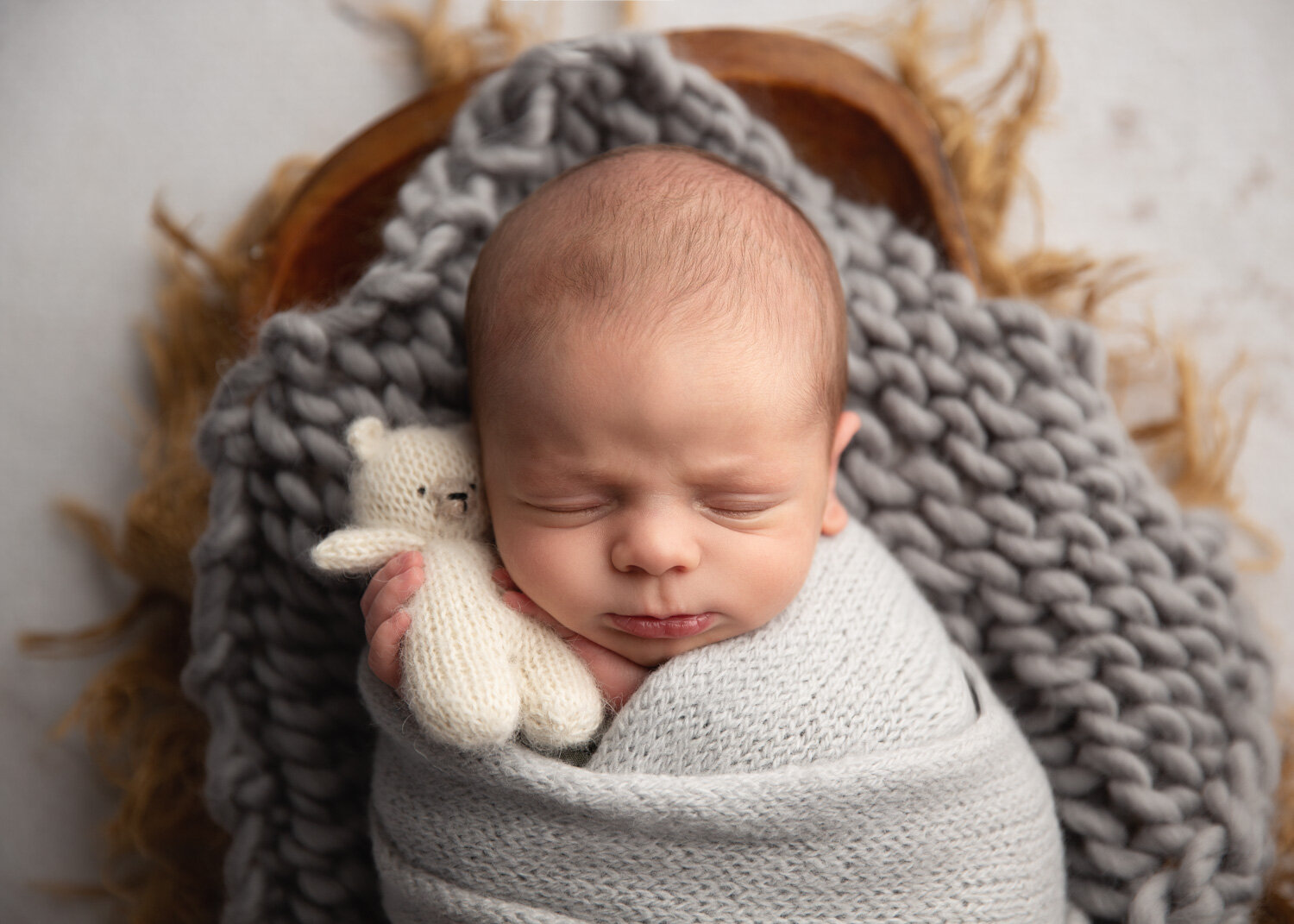  Adorable newborn baby boy holding teddy while wrapped up in crate for Newborn photography session in Winnipeg 