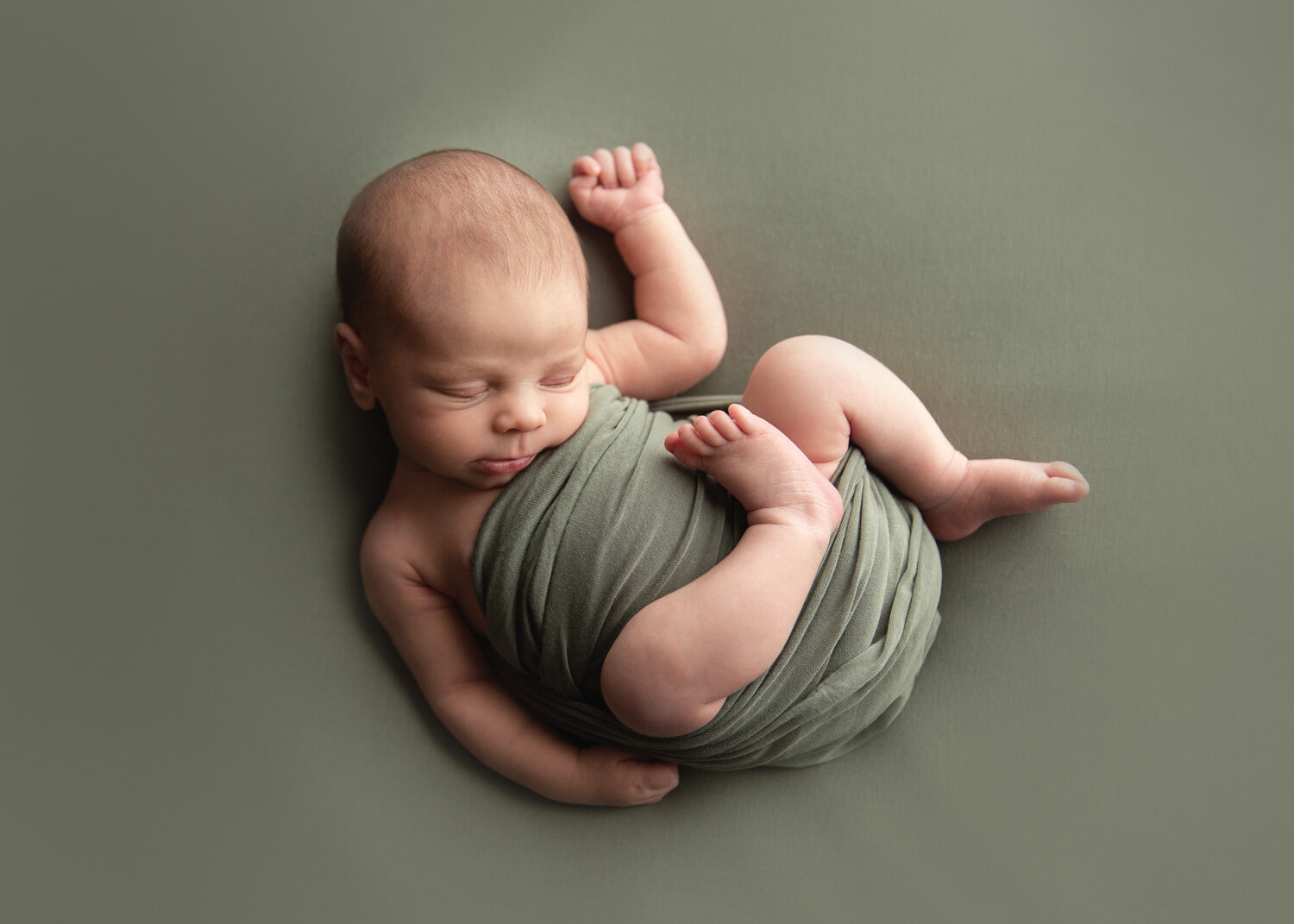  Baby boy in soft green relaxed posed with Sue Skrabek Photography in newborn studio in Winnipeg 