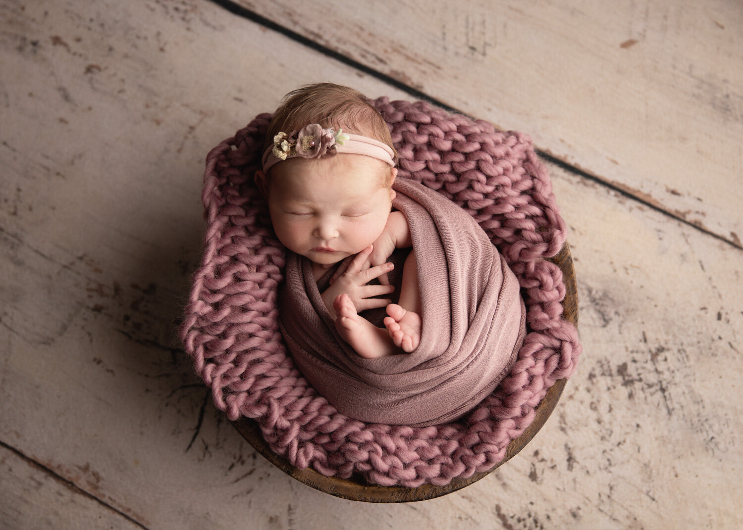  Baby girl curled up in mulberry wrap bowl set up in Newborn photography studio in Winnipeg 