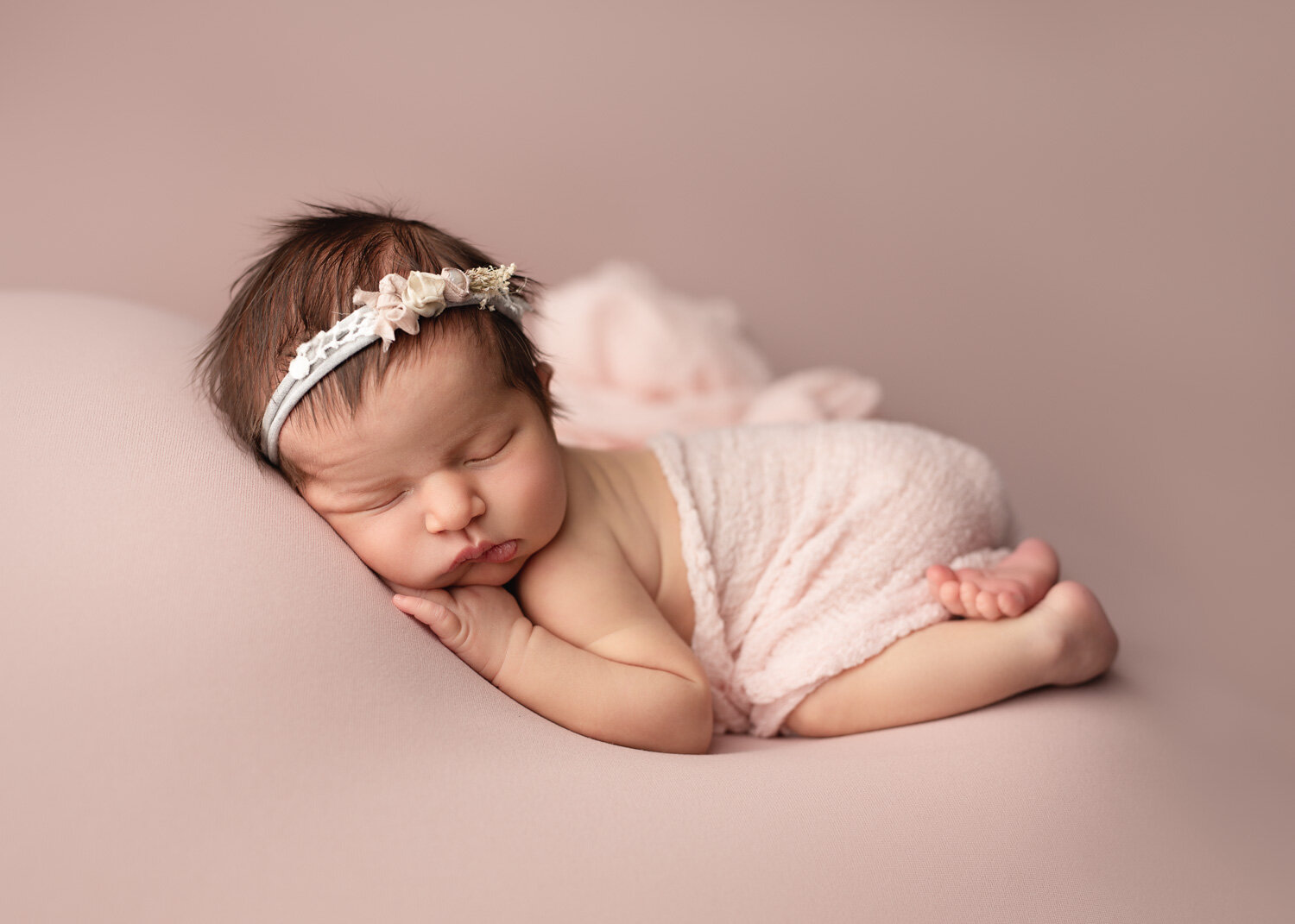  Classic blush set up with newborn baby girl lying with pink wrap for photoshoot in Winnipeg newborn studio 