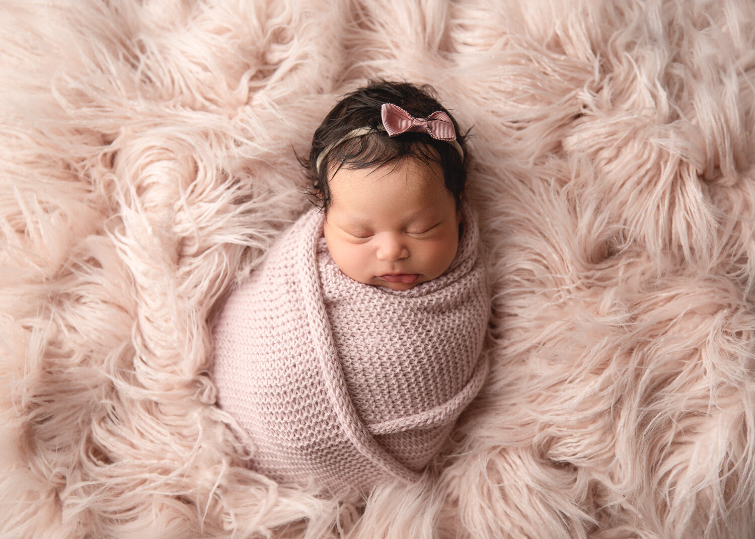  Cute blush simple bow headband on newborn girl wrapped up sleeping on blush flokati during baby photosession in Winnipeg 