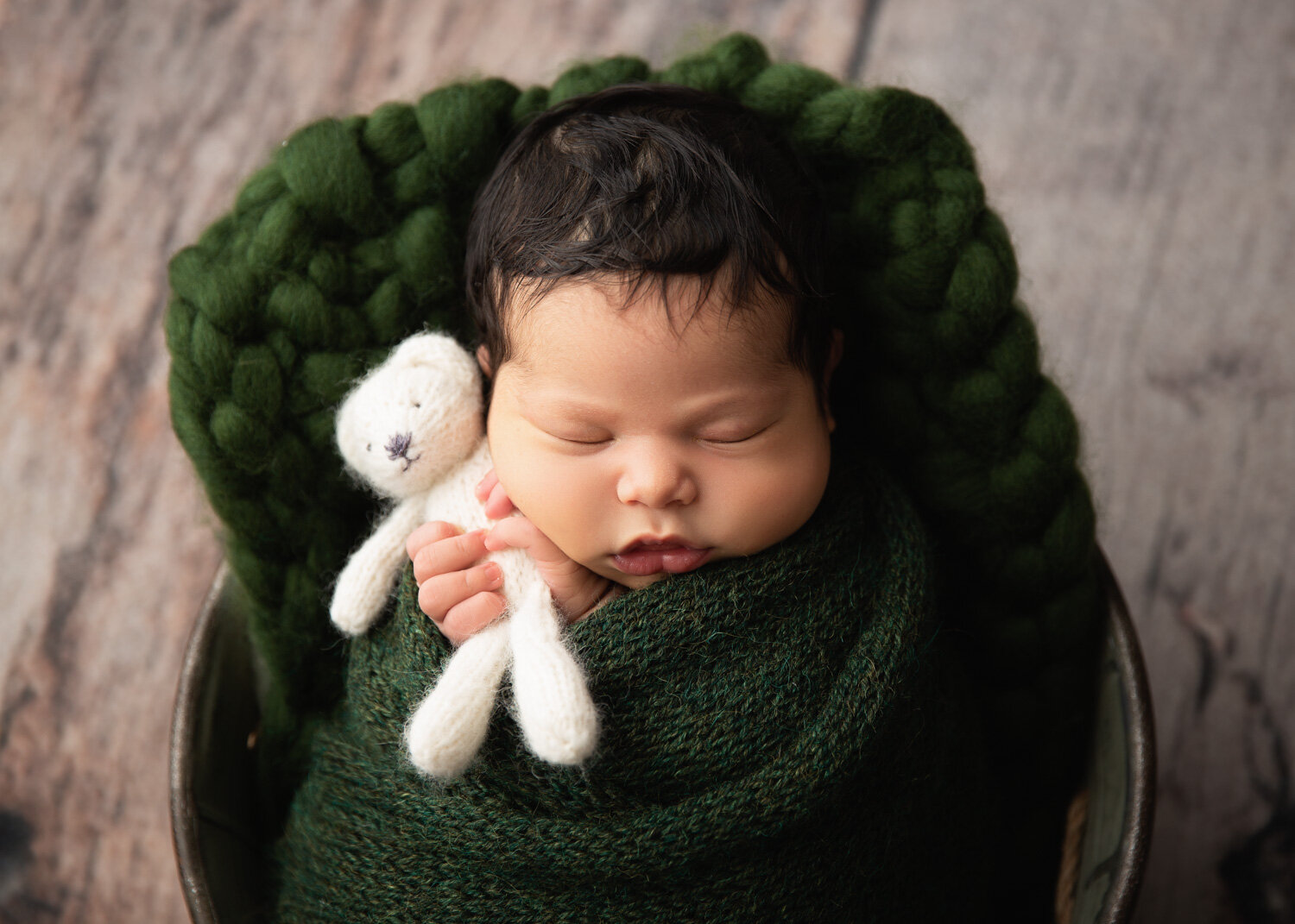  Baby boy in green holding white wool teddy with chubby cheeks in Winnipeg newborn baby photography studio 