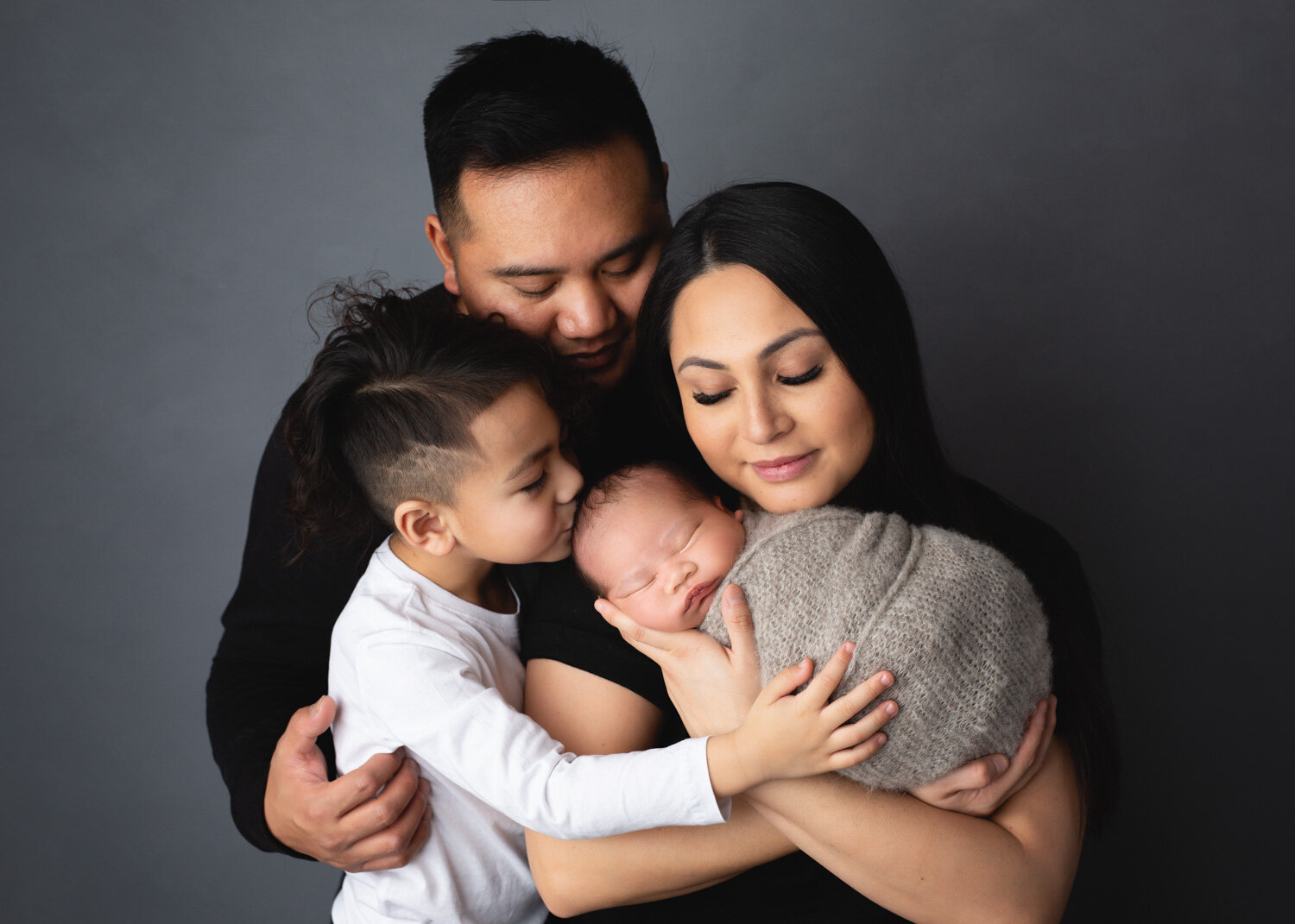  Parents and brother holding newborn baby boy in studio photosession in Winnipeg 