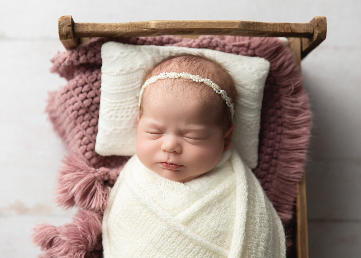  gorgeous baby girl wrapped in cream sleeping in bed during newborn photography session in Winnipeg 