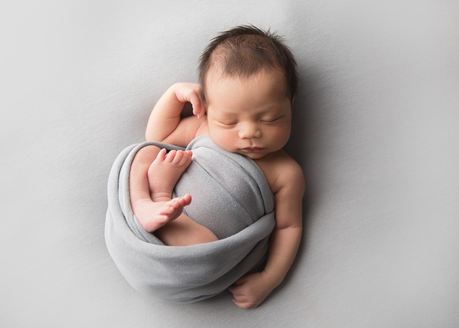  Baby boy relaxed pose in grey wrap for newborn photoshoot in Winnipeg with Sue Skrabek Photography in Winnipeg 
