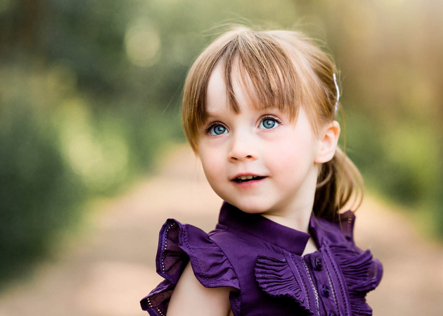  Beautiful blue eyed girl in fancy purple dress looking inquistive at park in WInnipeg 