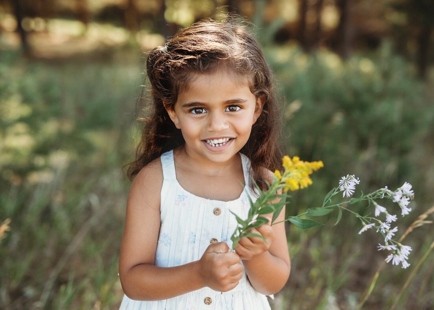  Gorgeous brown eyed girl in white dress holding wild flowers at park near WInnipeg 