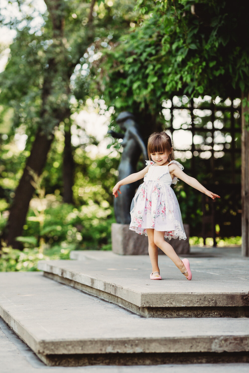  Beautiful young girl dancing on steps in garden for photoshoot in park near Winnipeg 