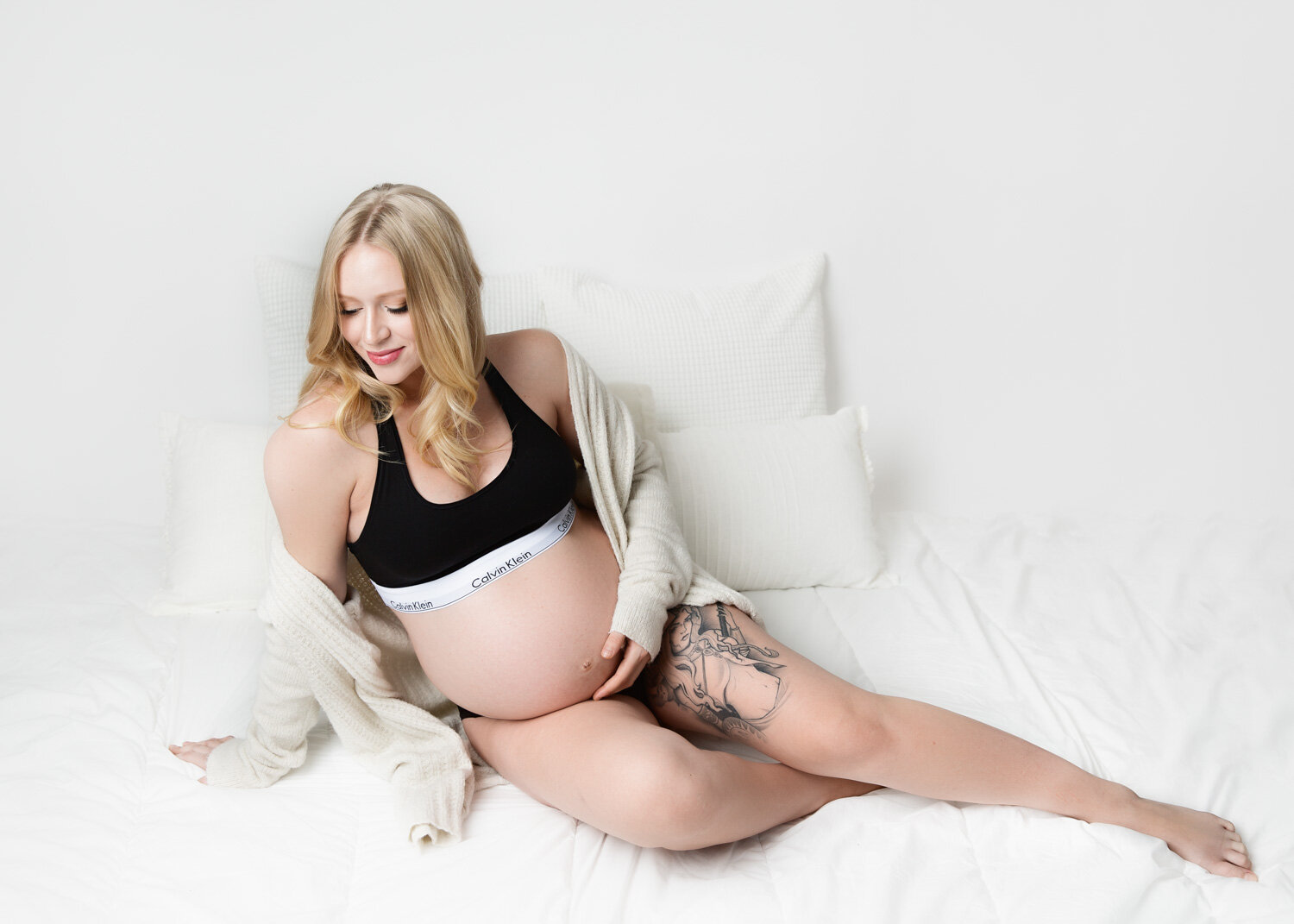  Gorgeous pregnant woman in Calvin Kleins lying on white bed for maternity photos in Winnipeg studio 