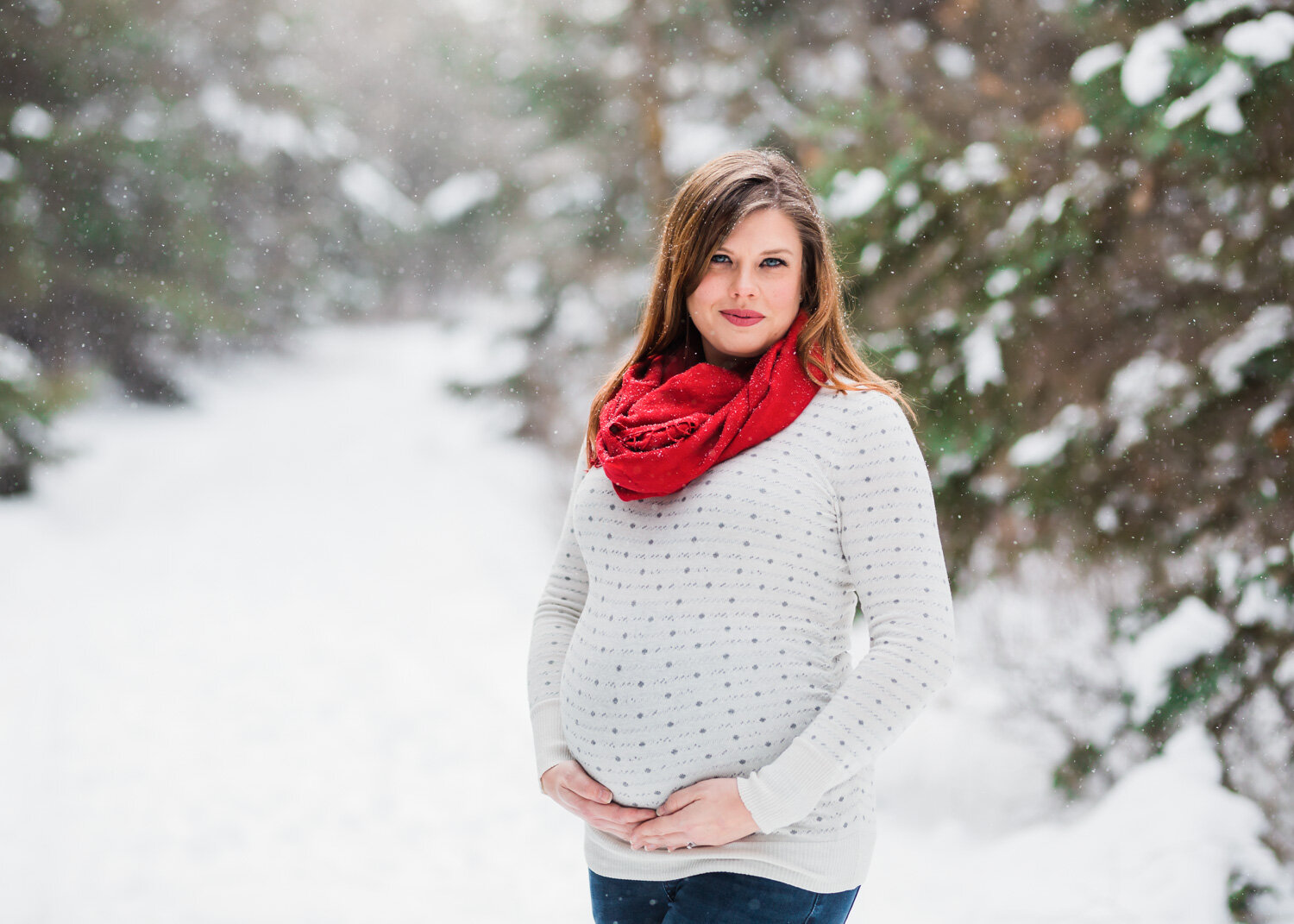  Beautiful pregnant woman smiling for maternity photos in the snowy everygreens near Winnipeg 