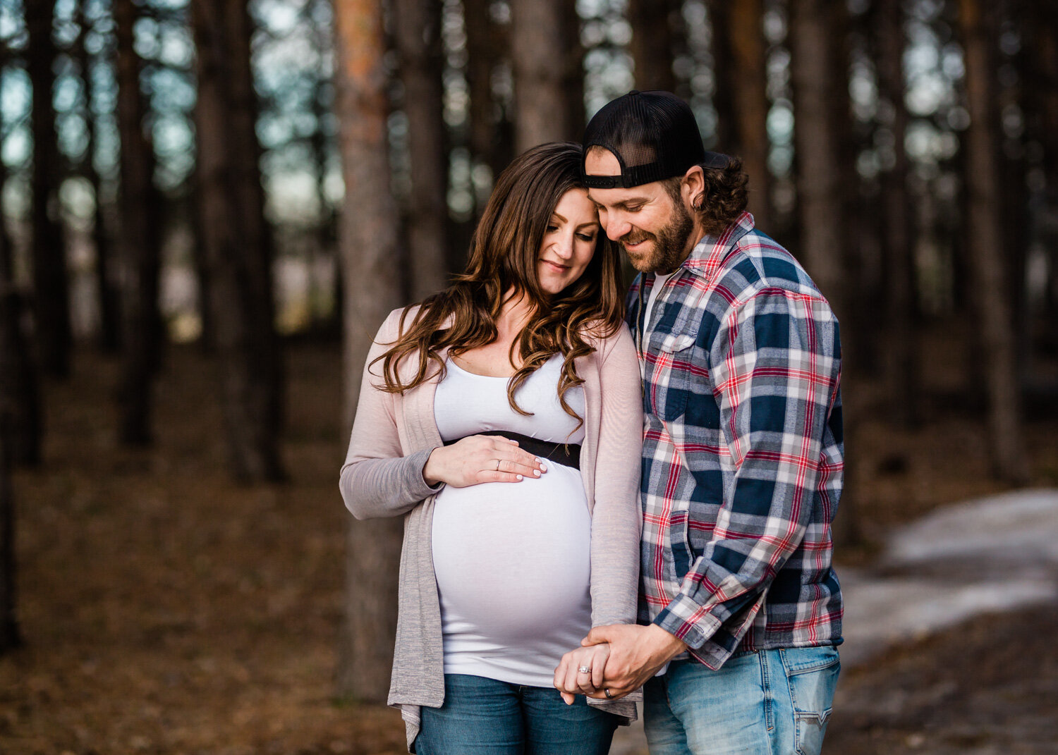  Couple cuddling in the tall pines of Birds Hill for maternity photos near WInnipeg 