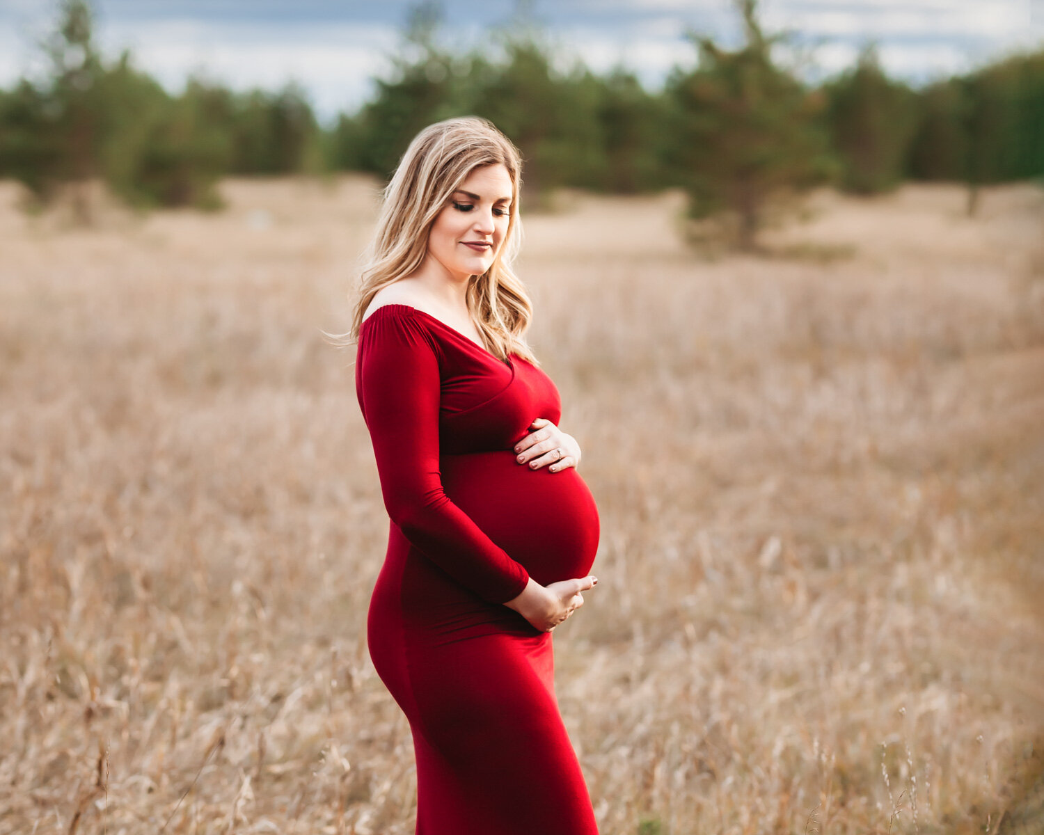  Gorgeous pregnant woman in red maternity gown in fall prairire grass for photoshoot near WInnipeg 