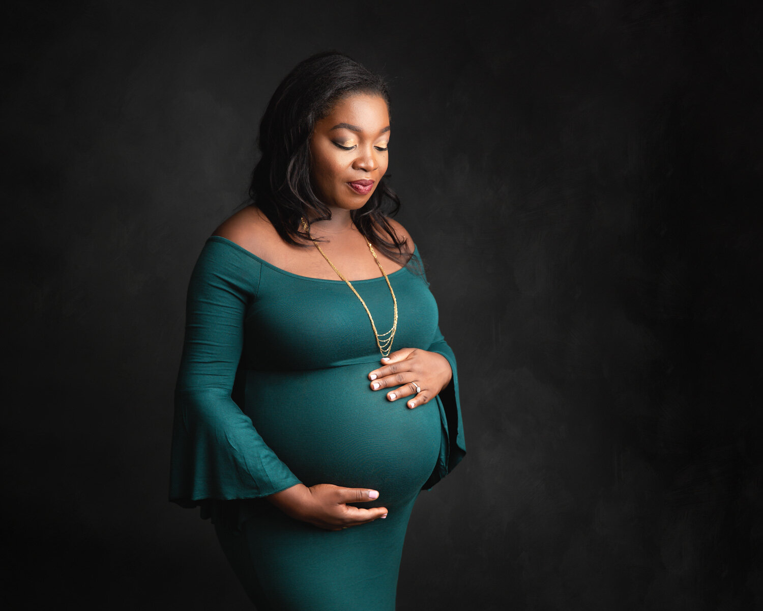  Beaming pregnant woman in green maternity gown for studio portraits in Winnipeg Studio 