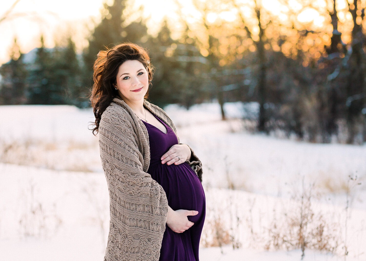  Gorgeous smiling pregnant mother in purple dress wrapped in blanket for winter maternity photosession in Winnipeg 