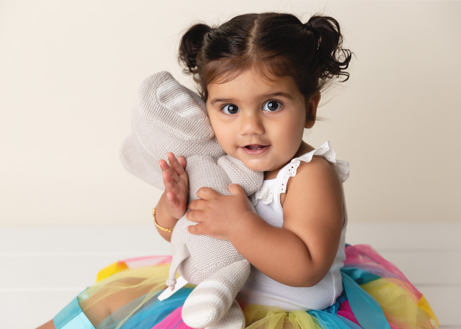  Gorgeous girl with bright wide eyes cuddling stuffy for child milestone photos in Winnipeg studio 