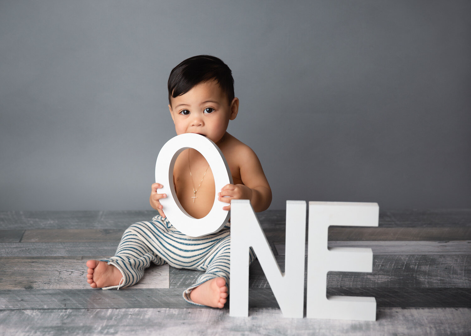  Boy holding white wooden ONE letters for child milestone session in Winnipeg photography studio 