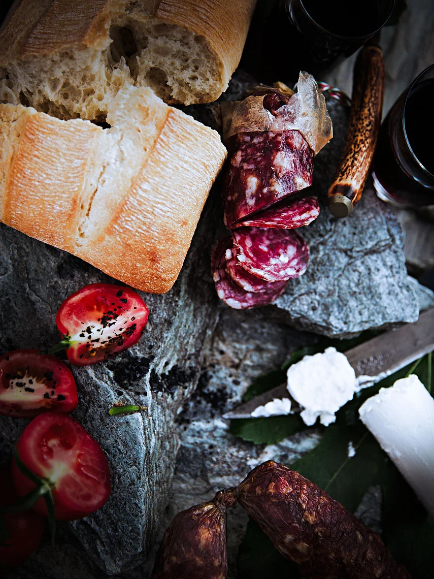 A TOAST 05 #truss #tomatoes #bread #focaccia #salami #glasses #red #wine #stone #slates #goats #milk #cheese #old #knife #bone #handle