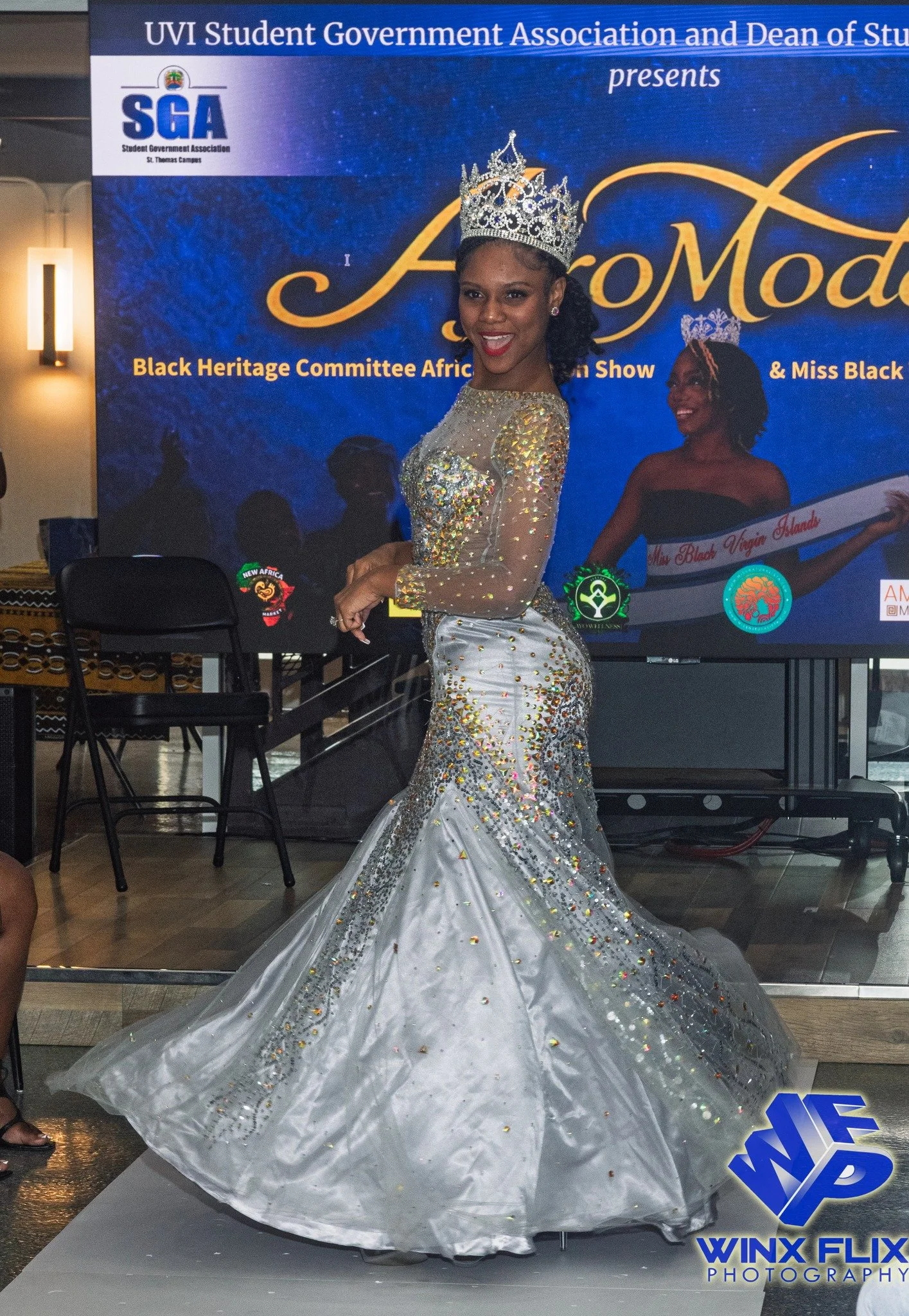 Miss UVI with crown in frozen spin wearing silver dress at top of runway.jpg