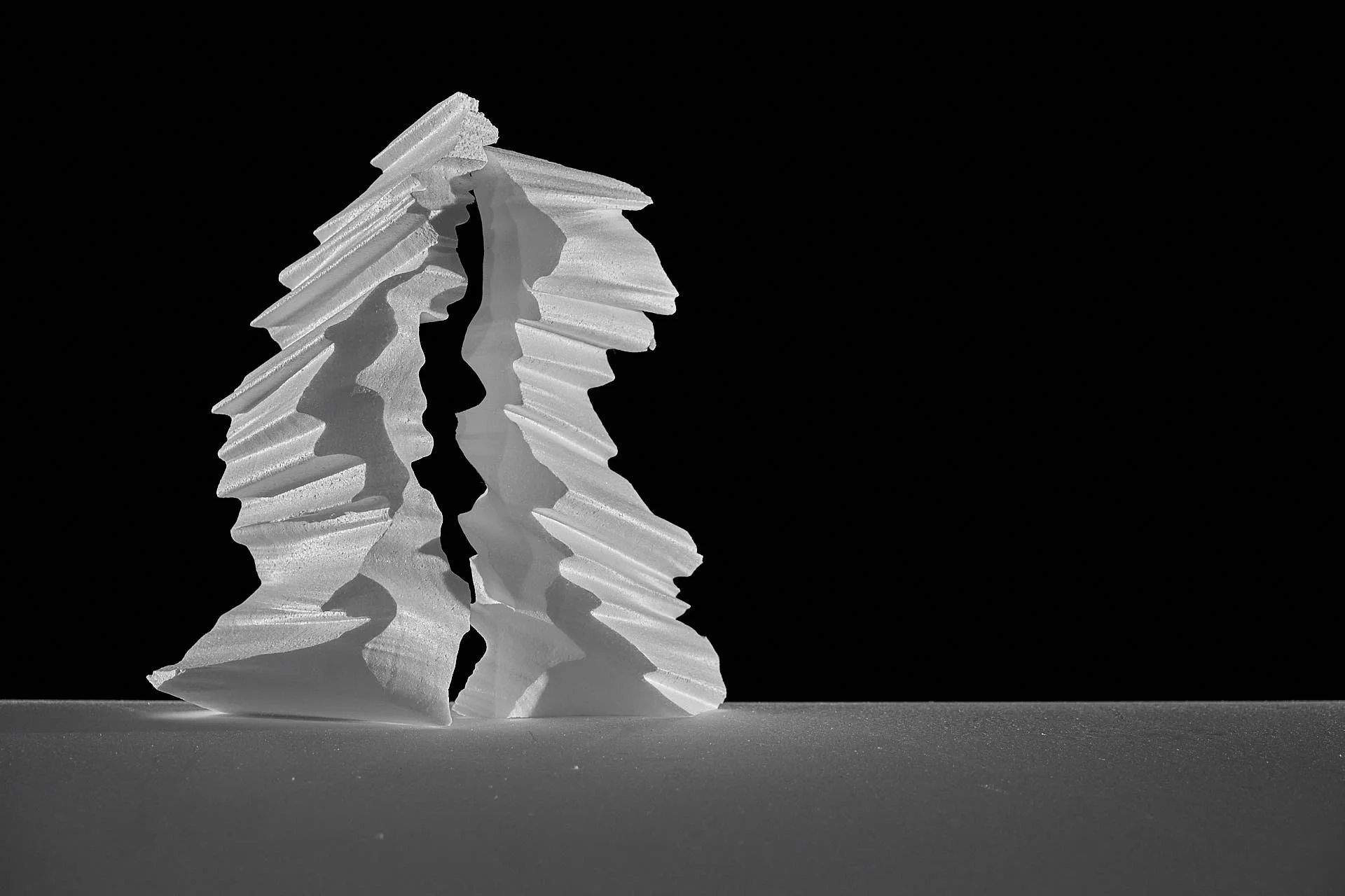 two sculptural pieces of white styrofoam against black background