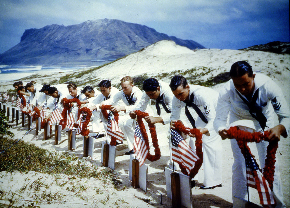 Uniformed American sailors place leis over the graves of their brothers in arms, in Spring 1942..jpg