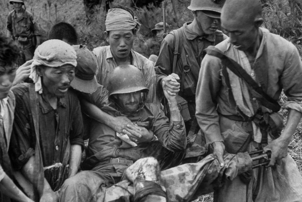 A group of soldiers helping an injured comrade in a jungle setting.