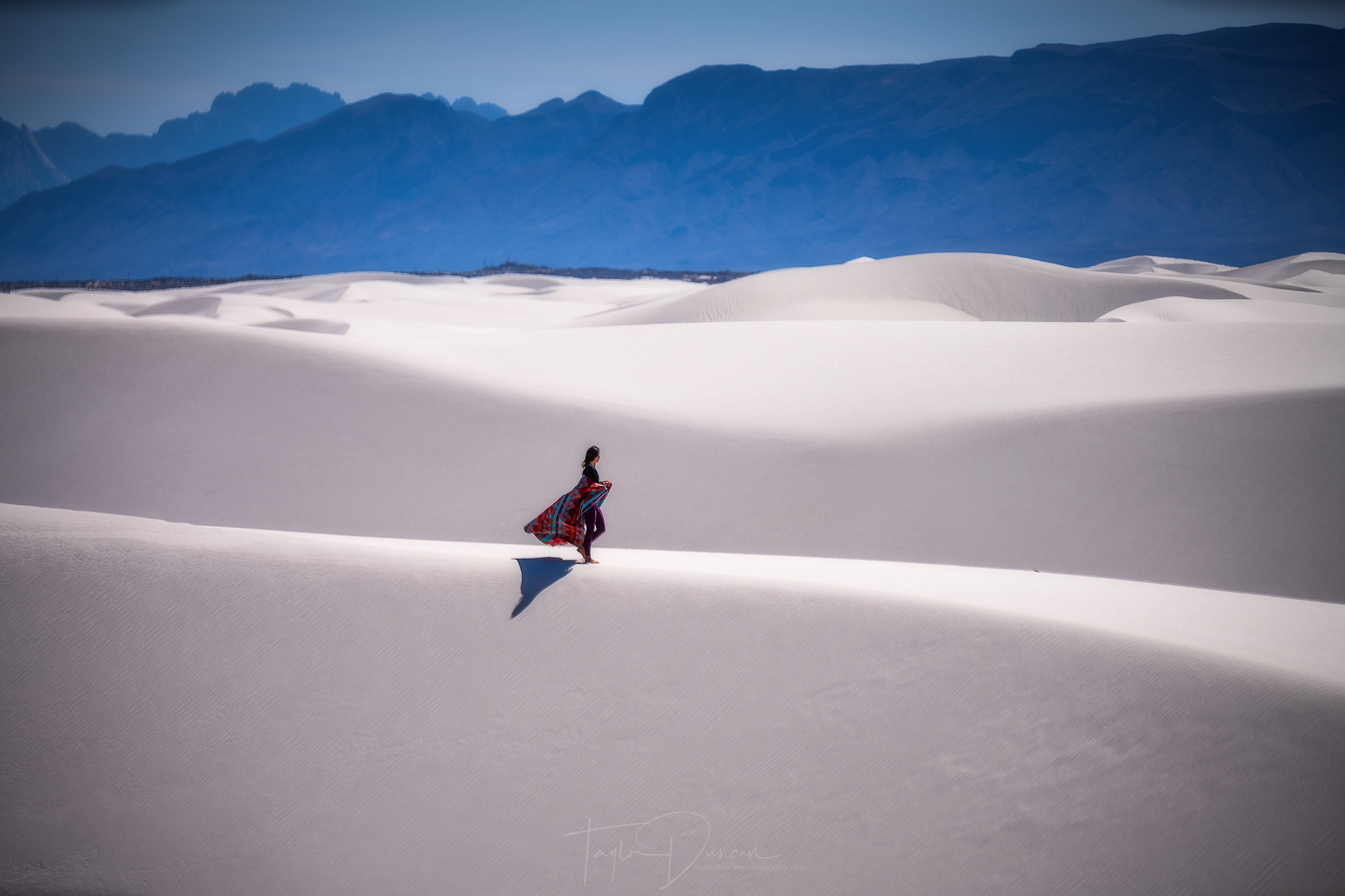 @dani_the_explorer takes a stroll across the white sand with the San Andres Mountains in the background
