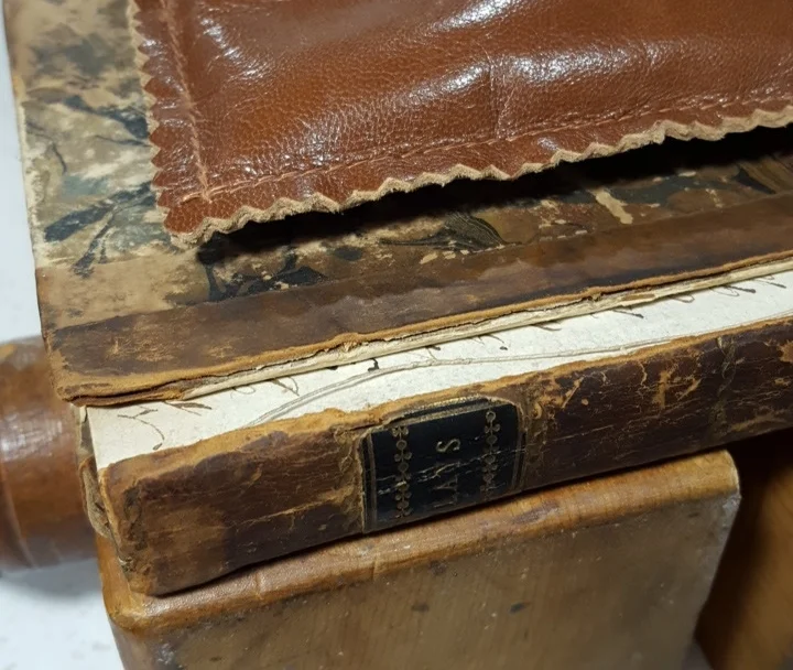 Preparing to reattach the covers of a half-leather book.