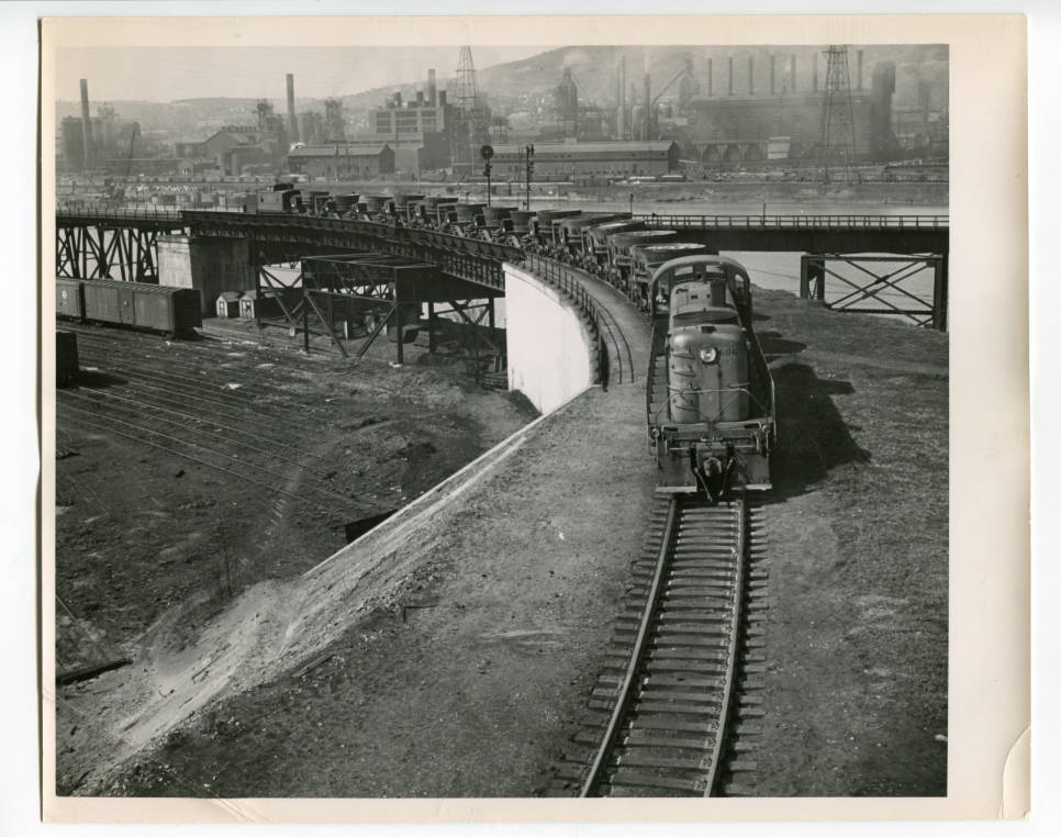 1940s/50s - Line of Pollock Co. cinder cars with US Steel's Edgar Thompson works in the background.