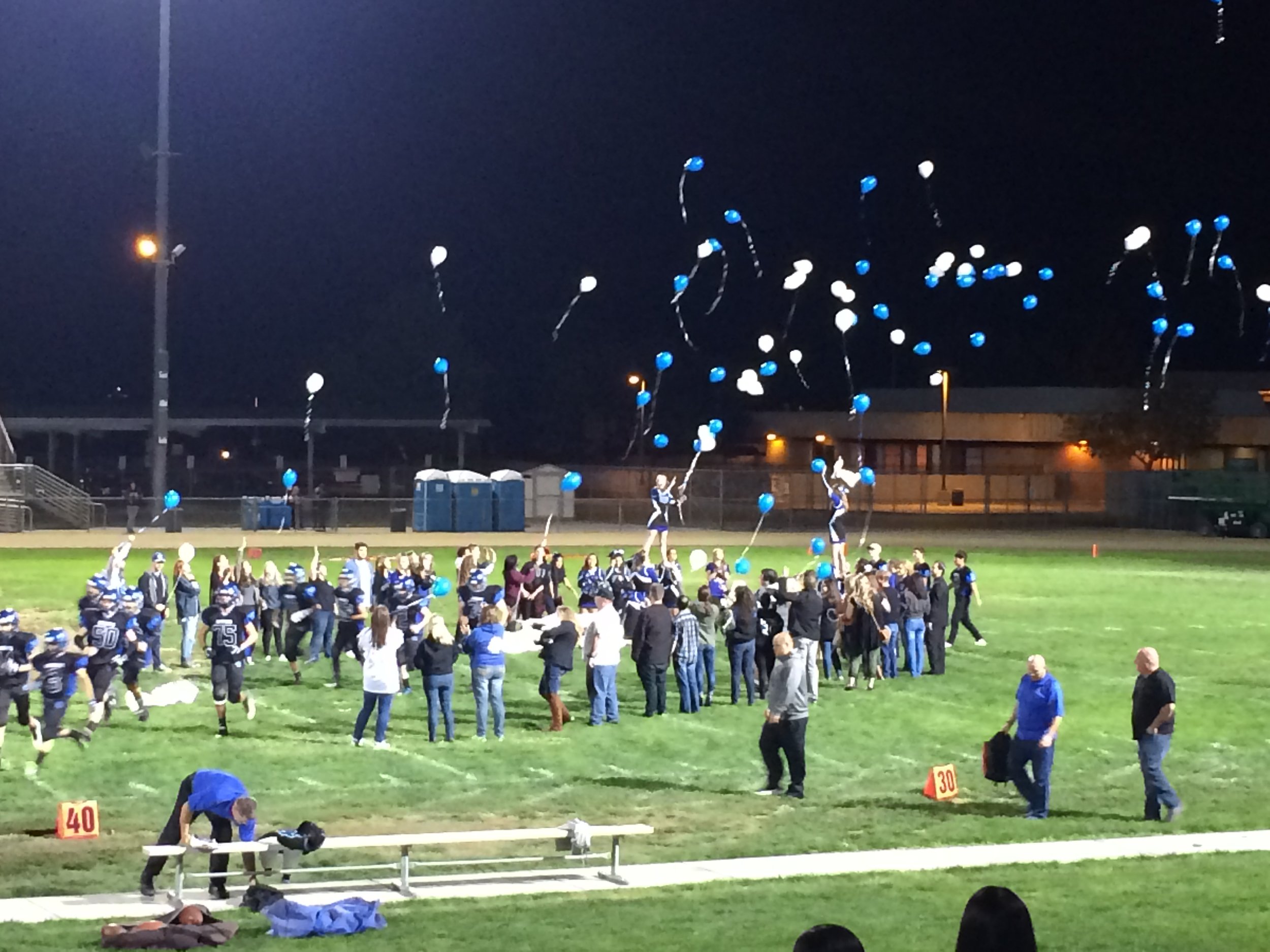 football field with a crowd and cheerleaders and balloons. 