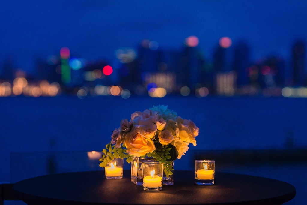 flower centerpiece with candles on a table at night. 